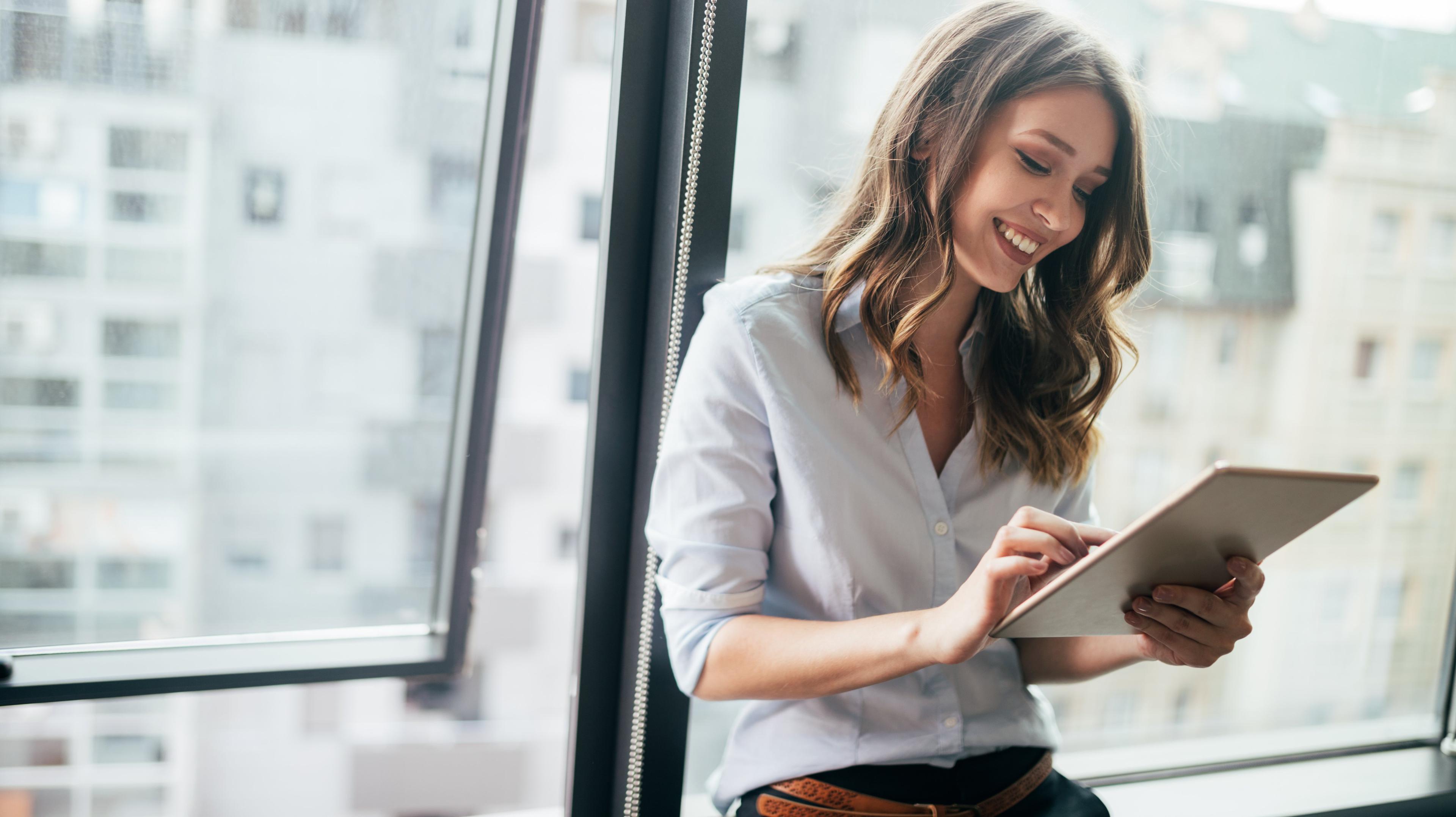 woman on her tablet in office with big windows