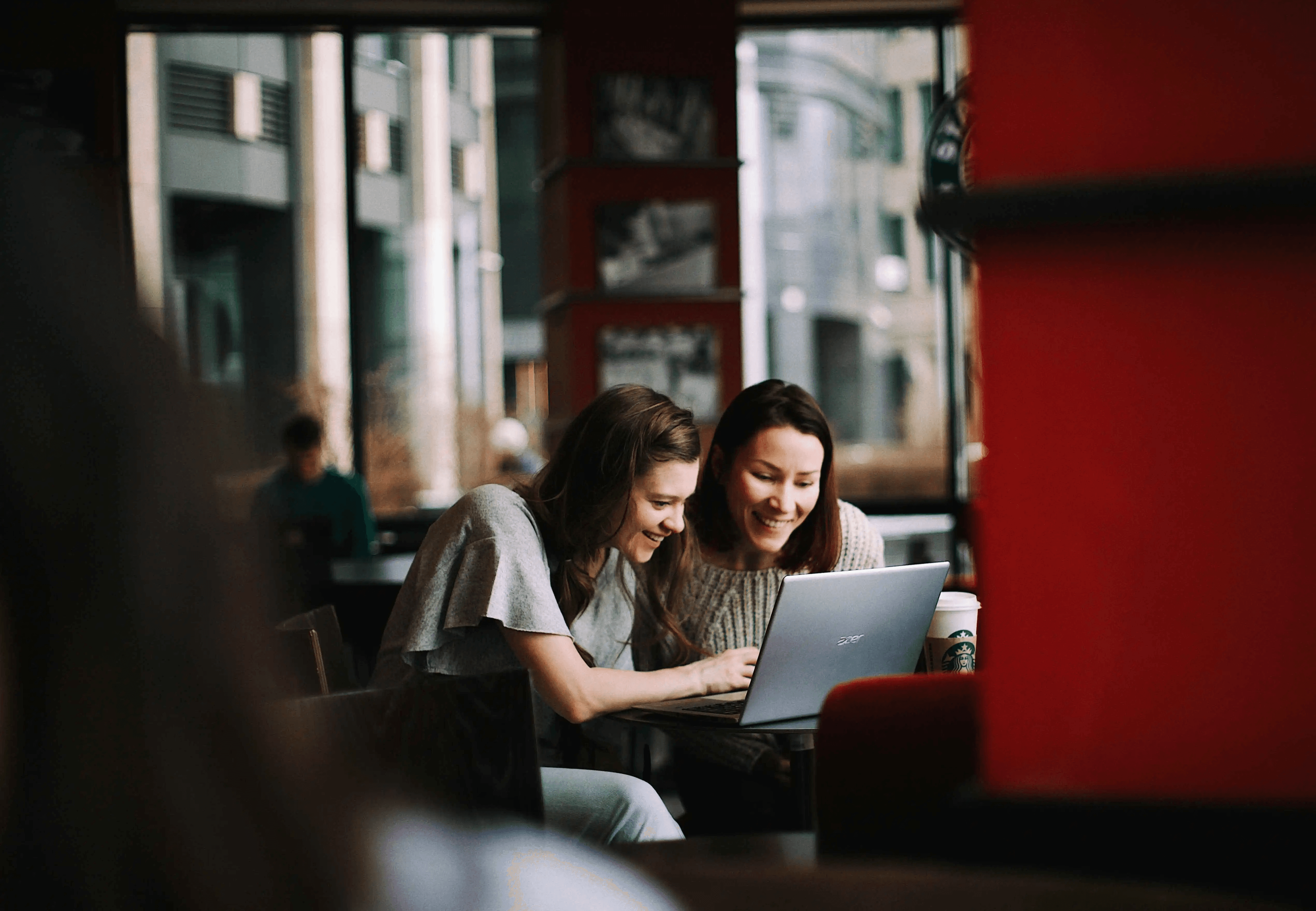 dos mujeres sonriendo frente a un computador